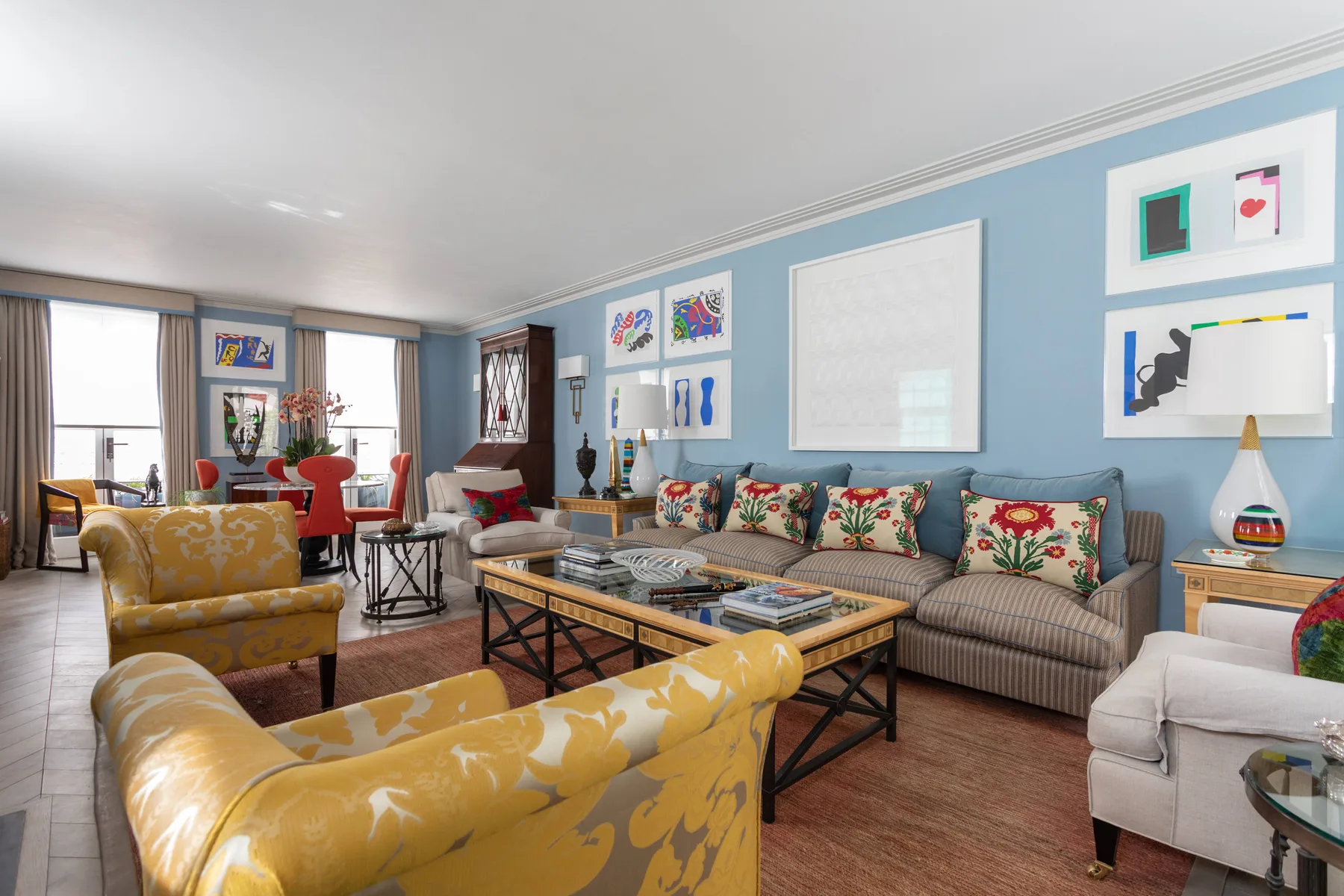 A bright living room with blue walls, patterned seating, and a coffee table.