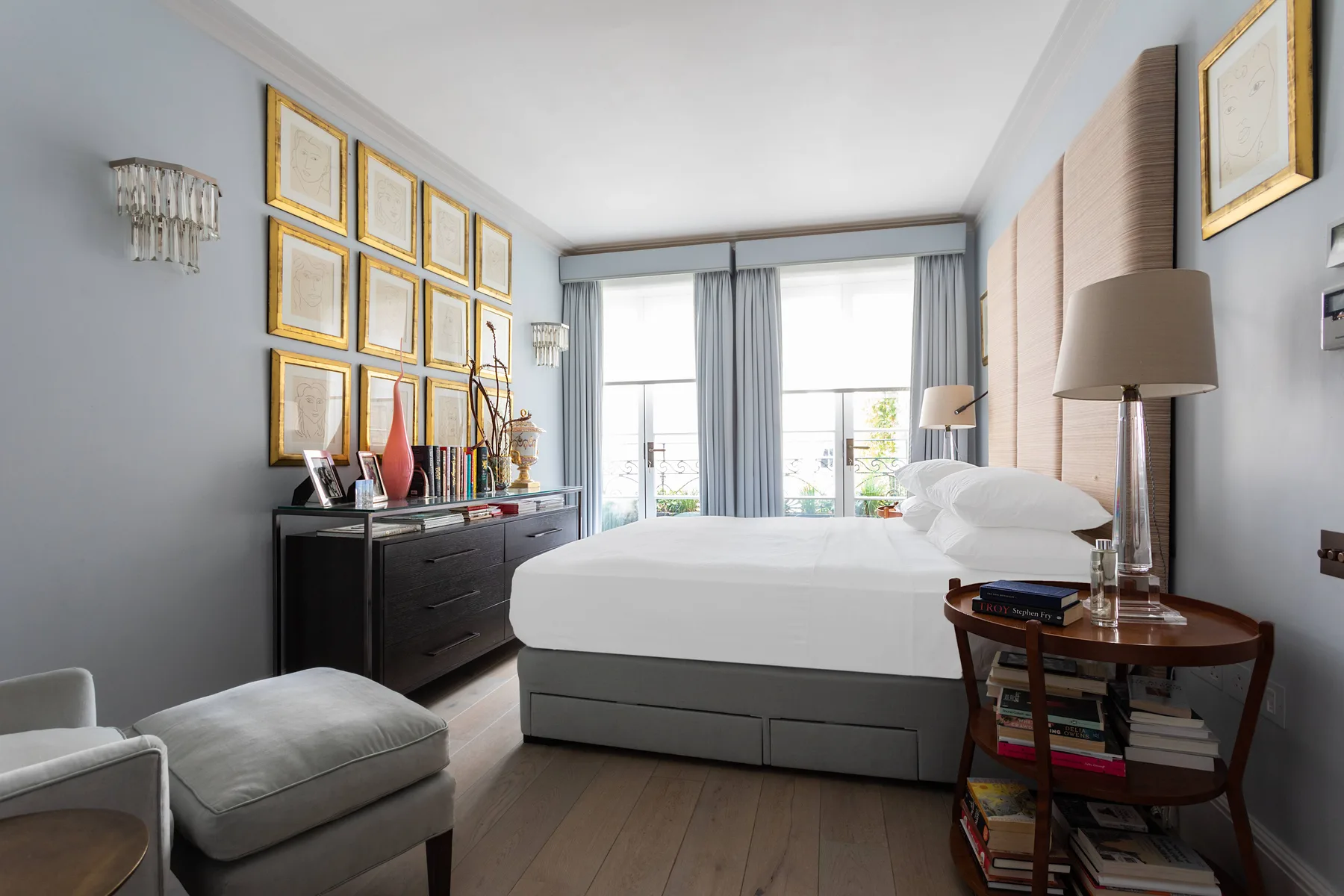 Un dormitorio con una cama bien tendida y grandes ventanas.