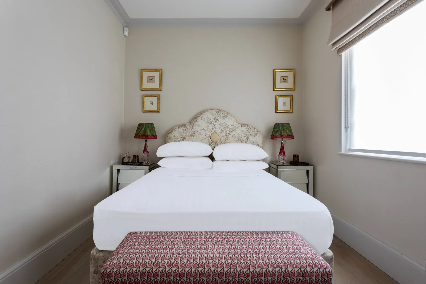 Un dormitorio con una cama bien arreglada y un banco estampado a sus pies.