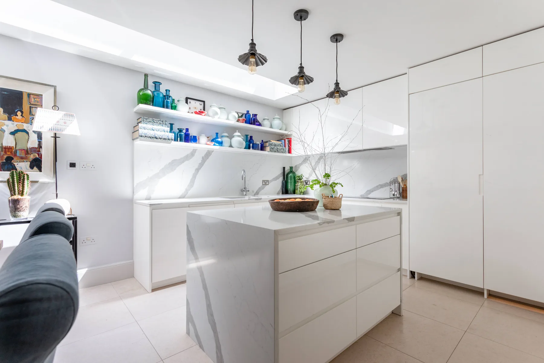 Una cocina moderna y luminosa con una isla central y estantes abiertos.