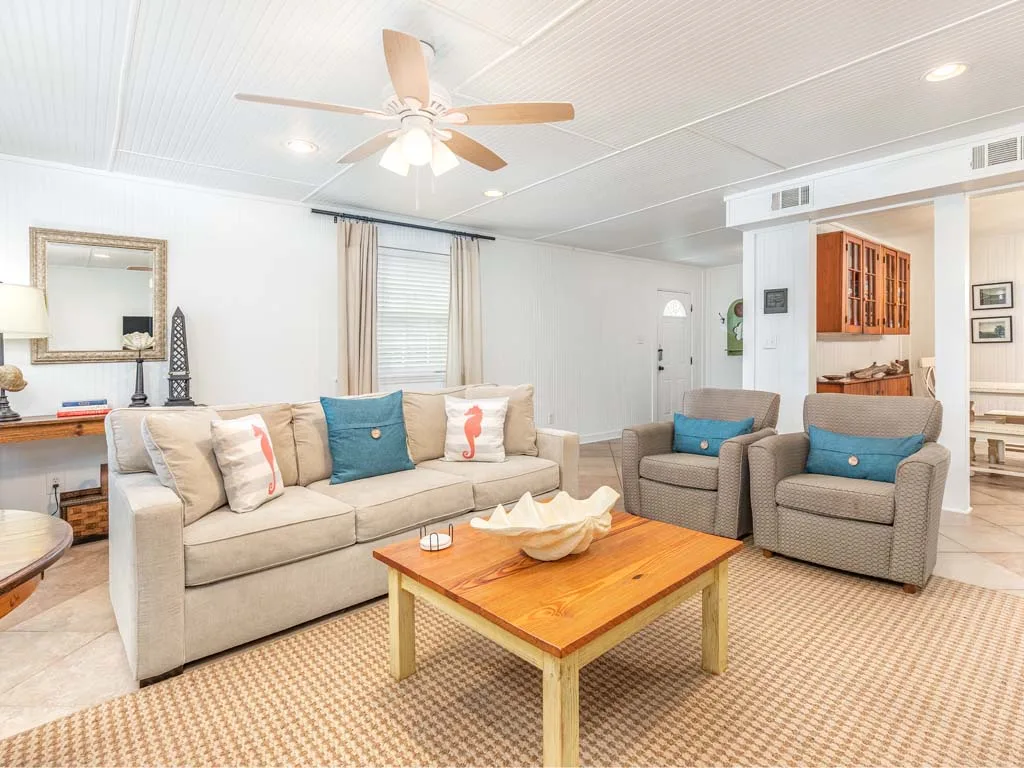 A bright living room with a sofa, two armchairs, and a wooden coffee table.