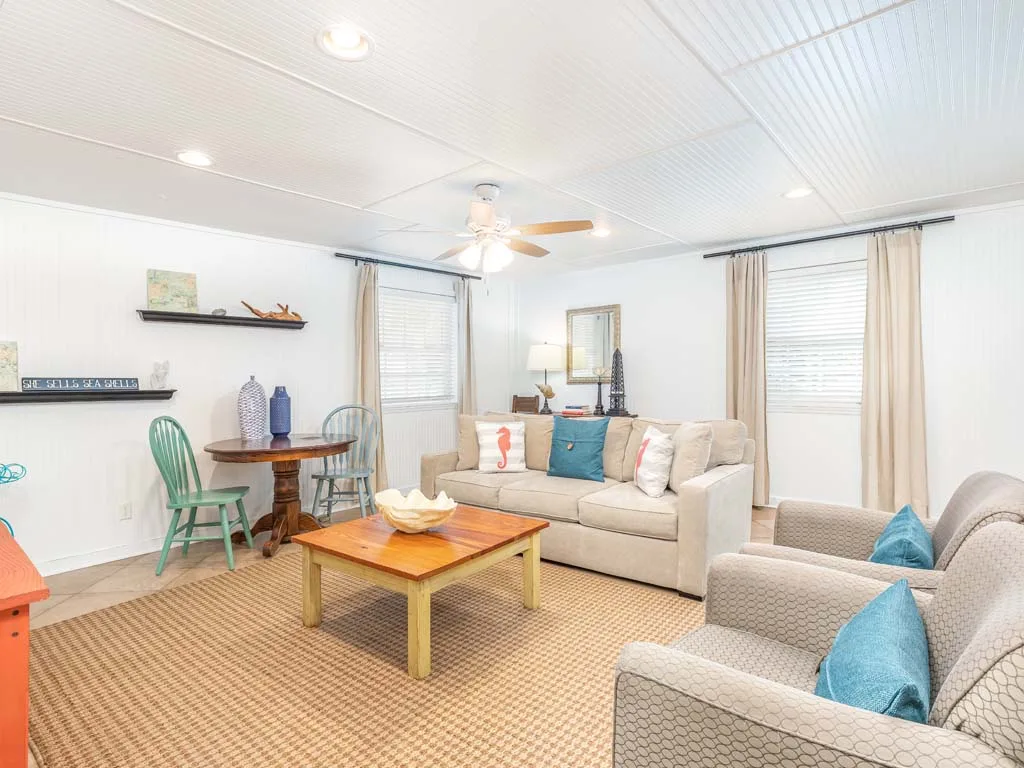 A bright living room with beige seating, a wooden coffee table, and large windows.