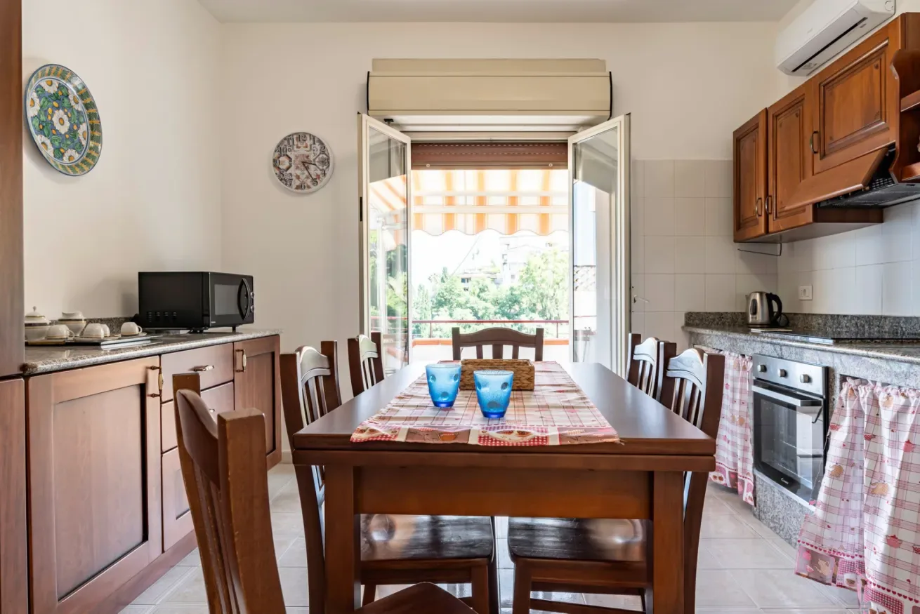 Comedor con una mesa de madera y sillas junto a una ventana abierta.