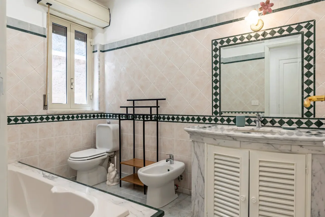 Un baño alicatado con bañera, inodoro, bidé y lavabo con espejo.