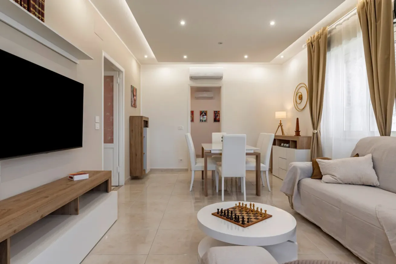 Una luminosa sala de estar y comedor con televisor, mesa de comedor y asientos.