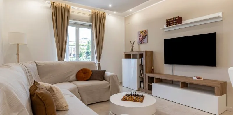 A bright living room with a wall-mounted television and a round coffee table.