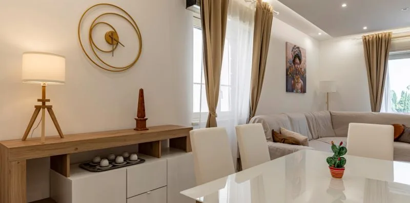 Un luminoso comedor y sala de estar con mesa, asientos y ventanas altas con cortinas.