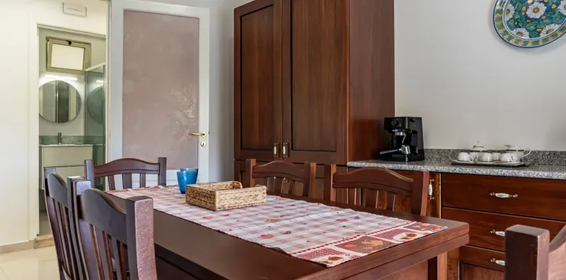 Un comedor con una mesa de madera, sillas y armarios empotrados.