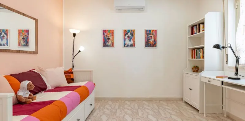 Un dormitorio con una cama colorida, cuadros y un escritorio.