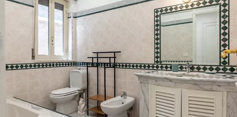 Un baño alicatado con inodoro, bidé y un espejo grande.