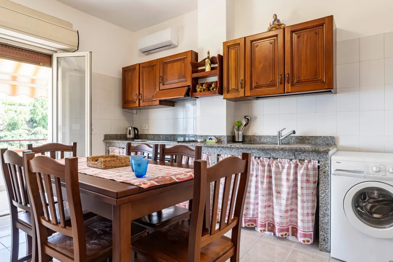 Una zona de comedor en la cocina con armarios de madera, una mesa y una lavadora.
