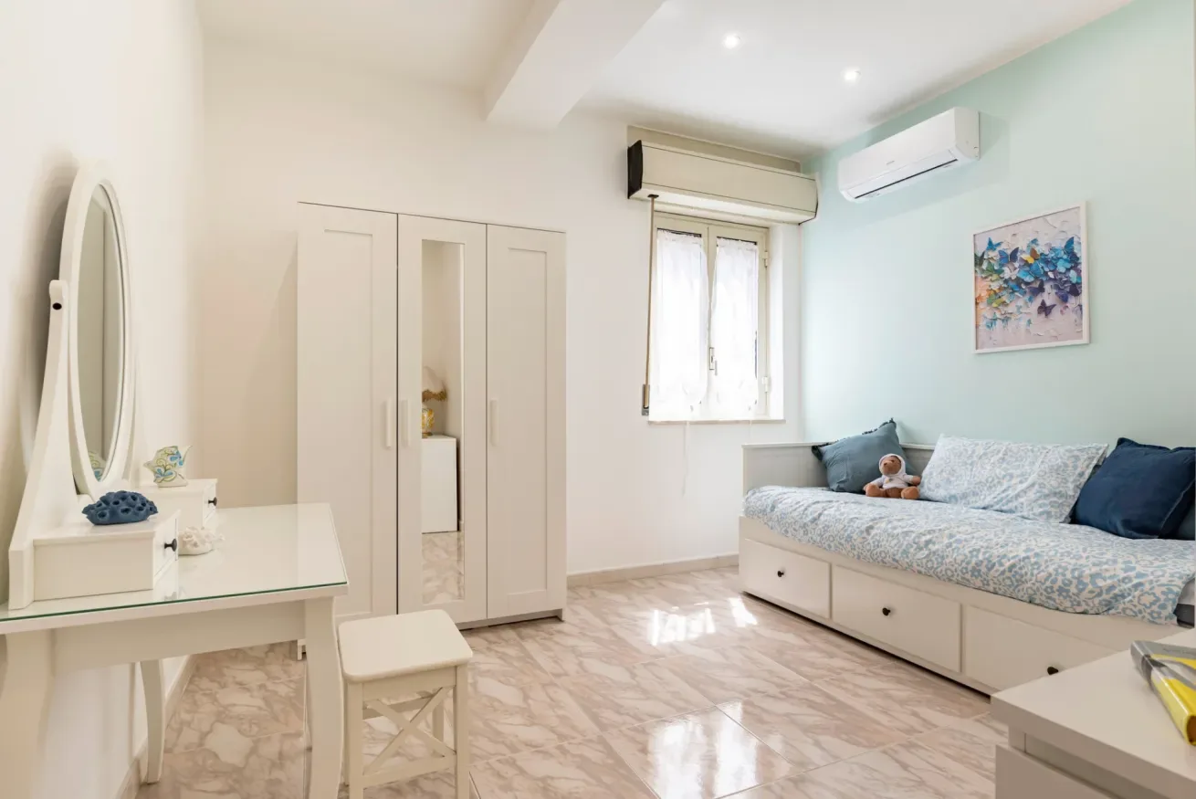 Un dormitorio luminoso con cama empotrada, armario y tocador.