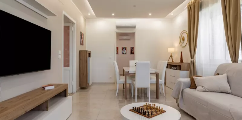 Una luminosa sala de estar y comedor con sofá, mesa y grandes ventanas.