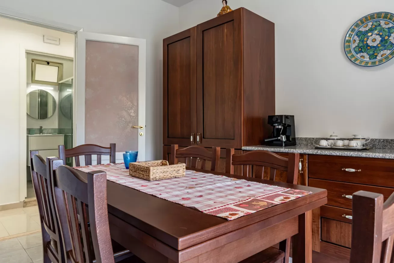 Un comedor con una mesa de madera y un armario alto.