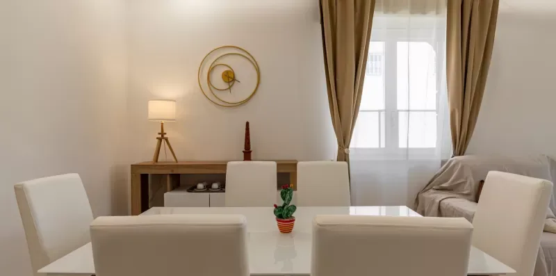 Un comedor con mesa y sillas junto a una ventana con cortinas.