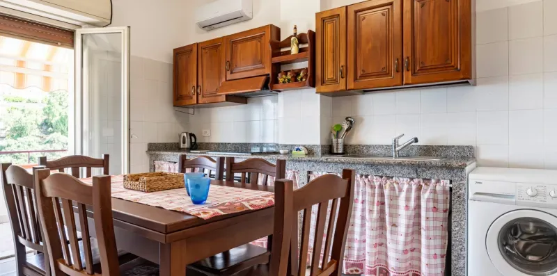 Una cocina y comedor con armarios de madera, una mesa y una lavadora.