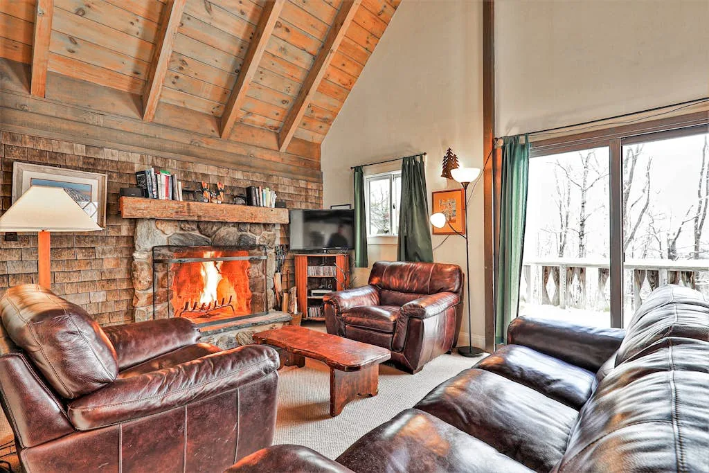 A living room with leather seating, a fireplace, and large windows.