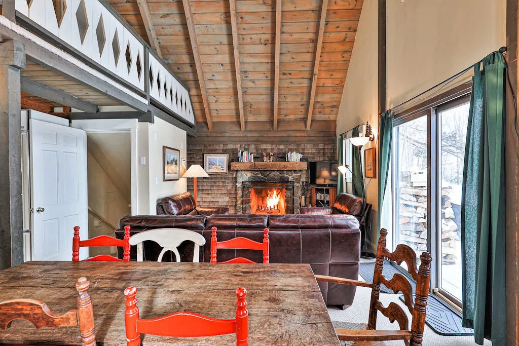 A rustic living room with a fireplace, seating, and a dining table.