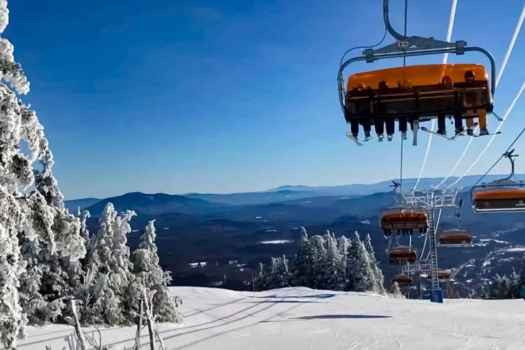 A snowy ski slope with a chairlift and frosted trees beneath a clear sky.