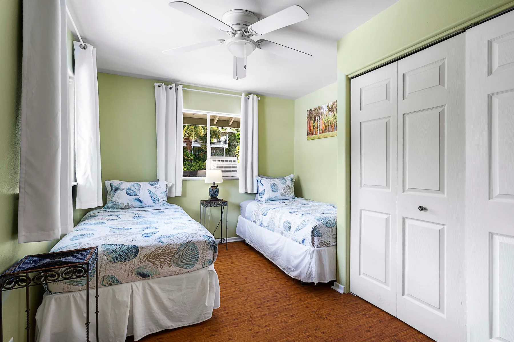 Un dormitorio con dos camas, una ventana y un ventilador de techo.