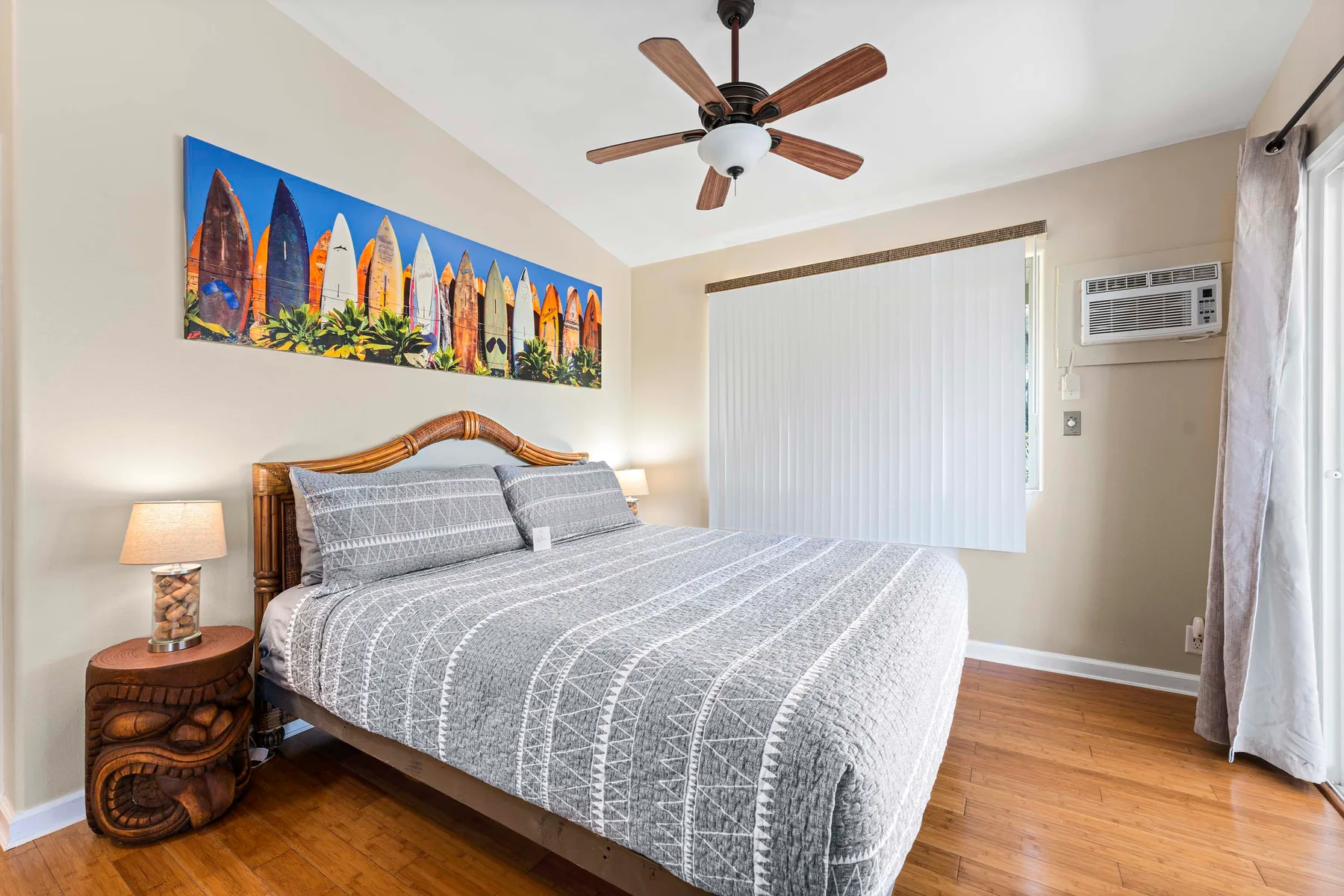 Un dormitorio con una cama tendida y un colorido cuadro de tablas de surf en la pared.