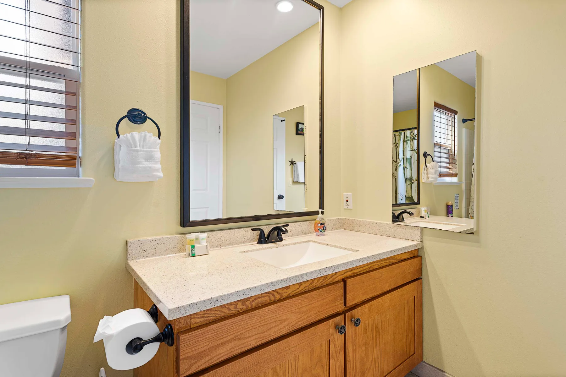 Un tocador de baño con lavabo, gabinetes de madera y espejos.