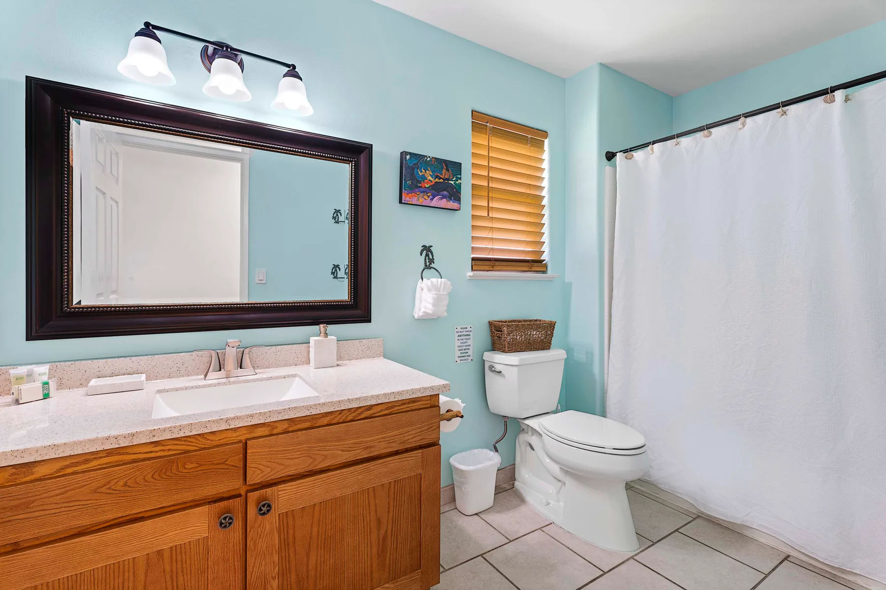 Un baño con un tocador de madera, inodoro y cortina de ducha blanca.