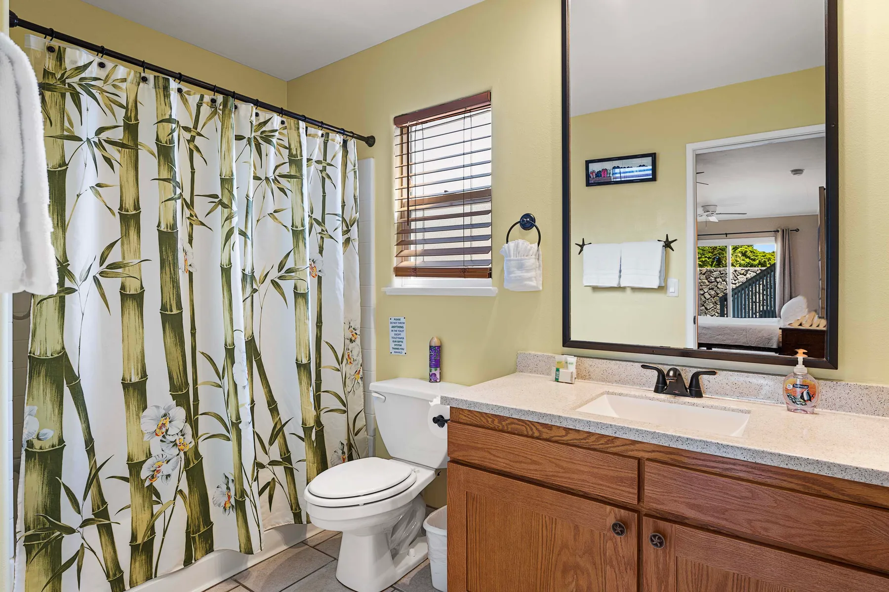 Un baño con lavabo, inodoro y cortina de ducha con motivos botánicos.