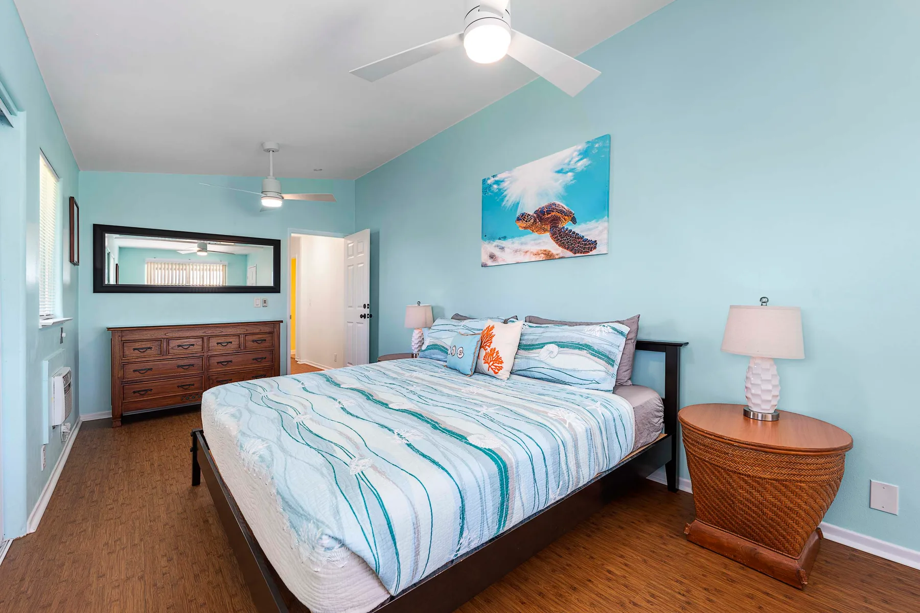 Un dormitorio con una cama, mesitas de noche y arte mural de temática oceánica.