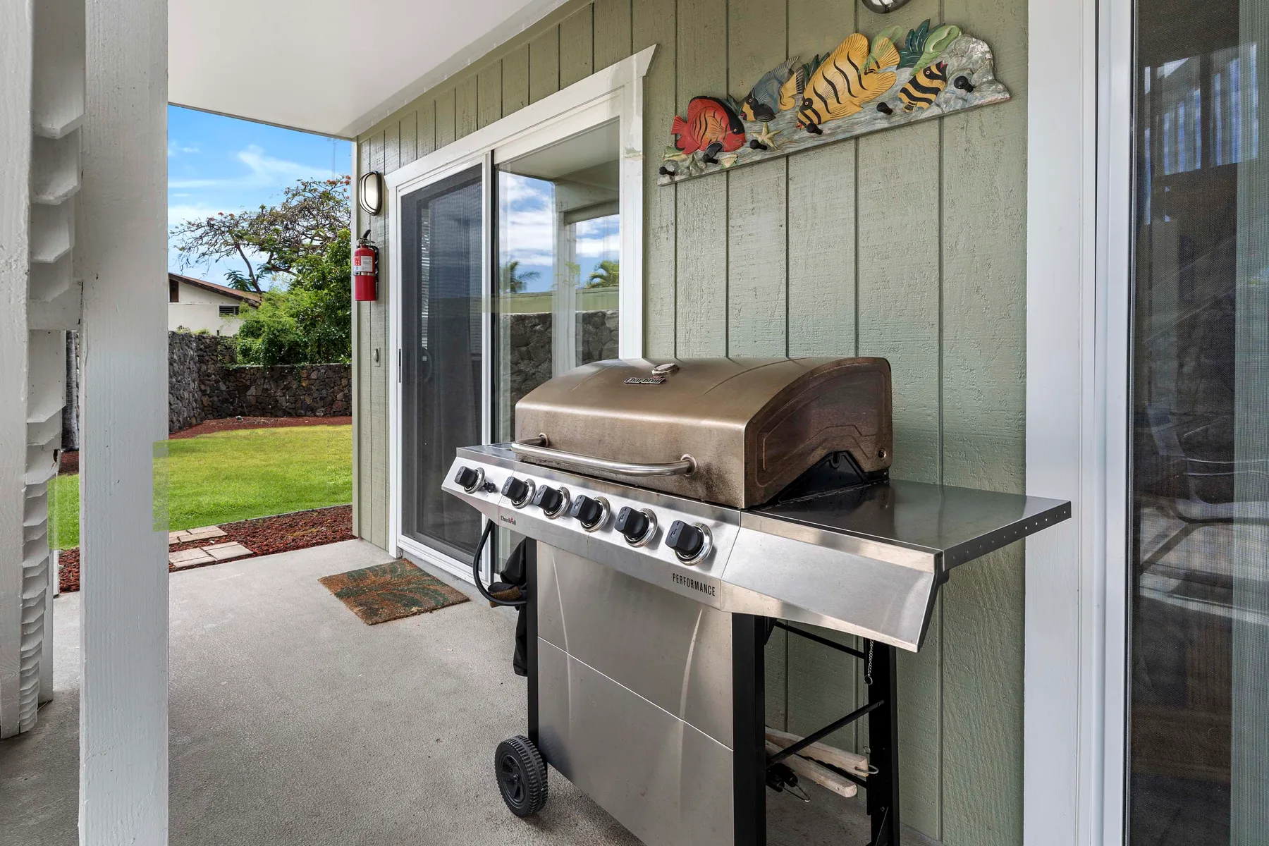 Un patio cubierto con una parrilla de acero inoxidable junto a puertas corredizas de vidrio.
