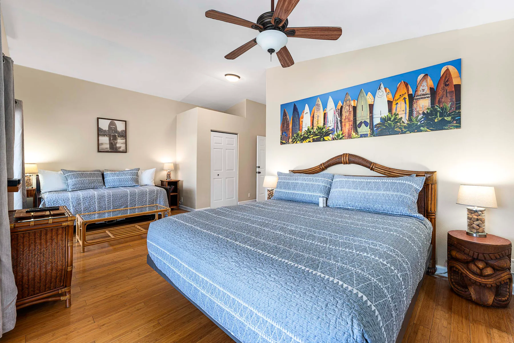 Un dormitorio con dos camas vestidas con ropa de cama azul y arte colorido en la pared.