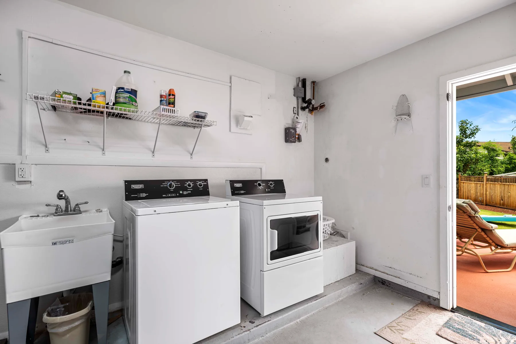 Un cuarto de lavado con lavadora, secadora y fregadero de servicio.
