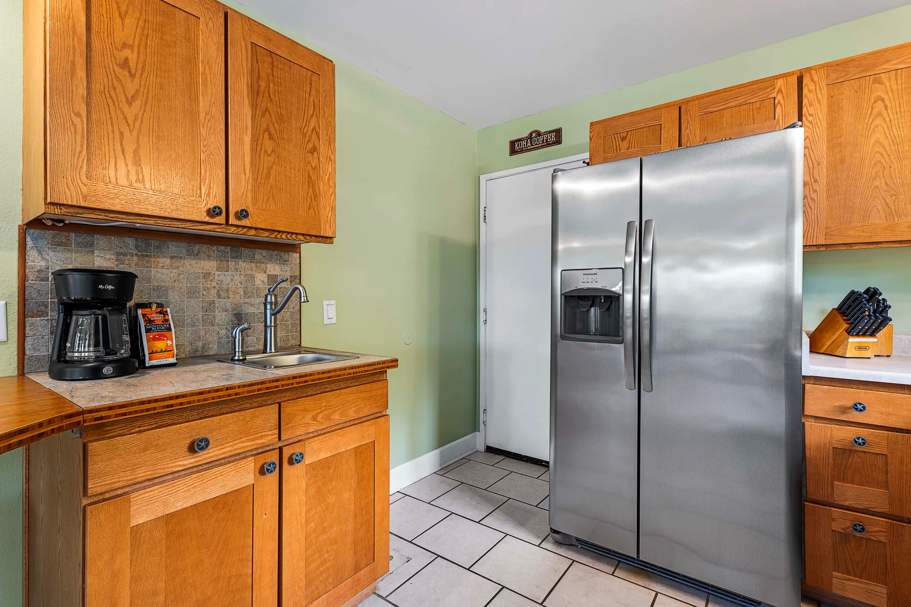 Una cocina con gabinetes de madera, una encimera y un refrigerador de acero inoxidable.