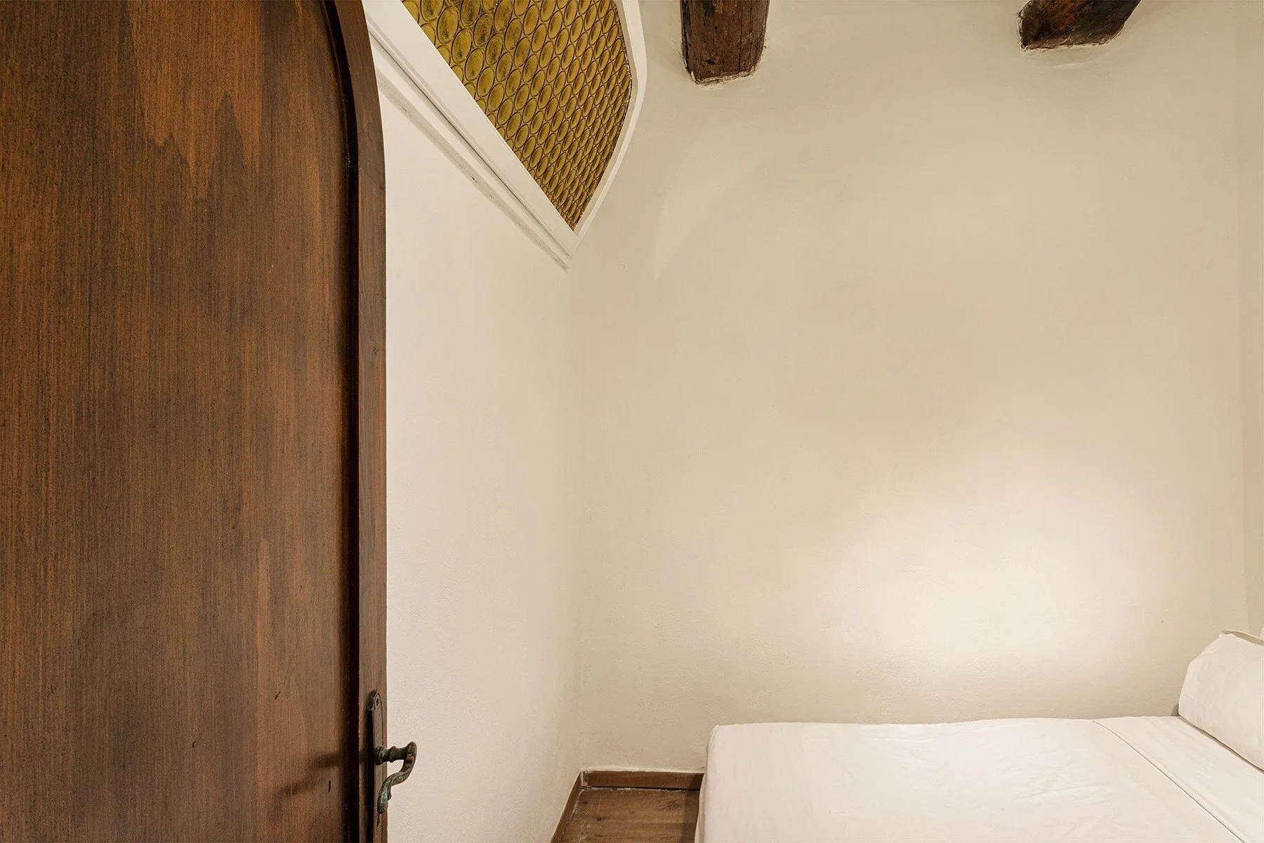 A bedroom with a white bed beside a wooden door.
