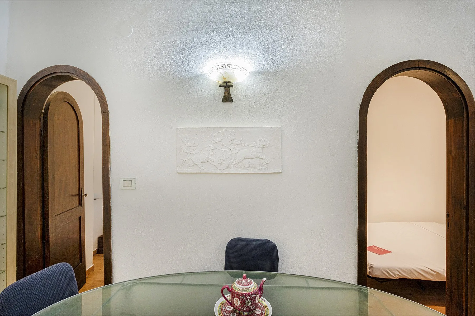 A dining area with a glass table between two arched doorways.