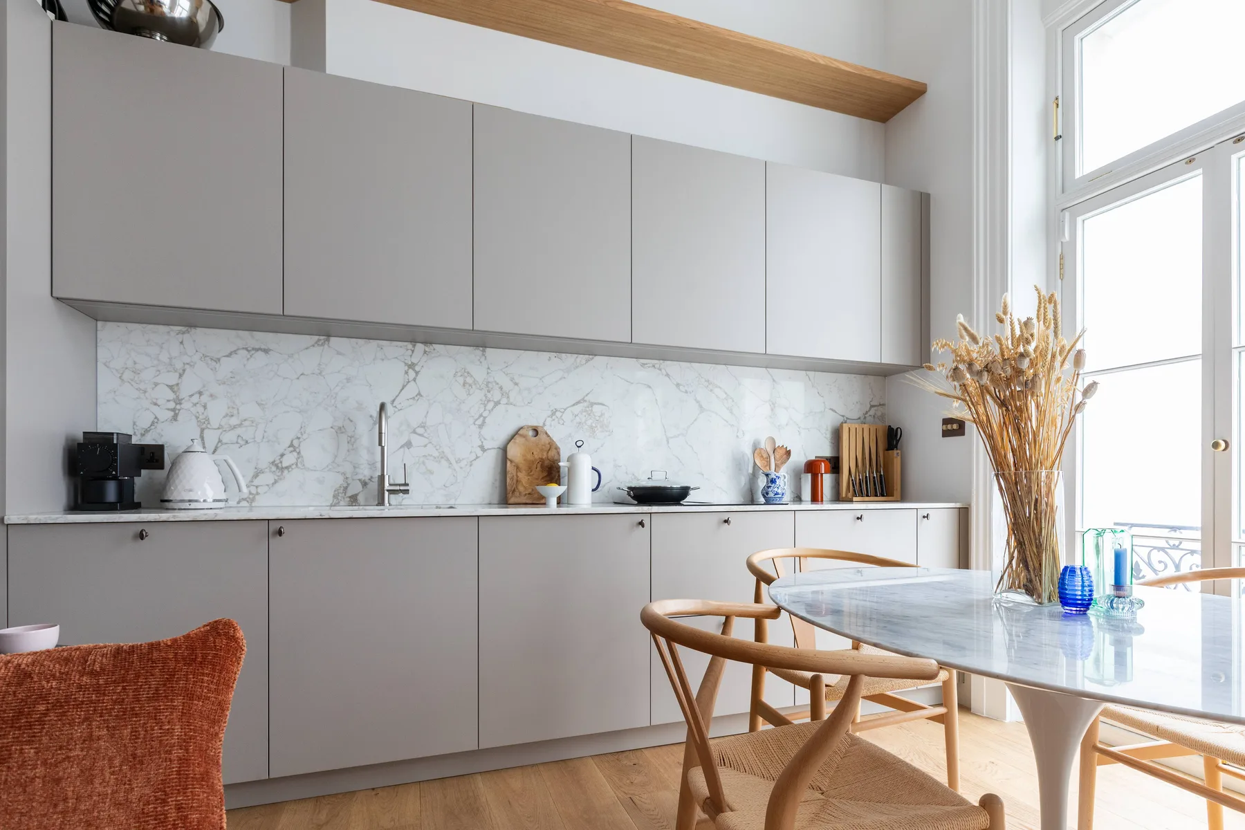 Una cocina moderna y luminosa con gabinetes grises y una mesa junto a la ventana.