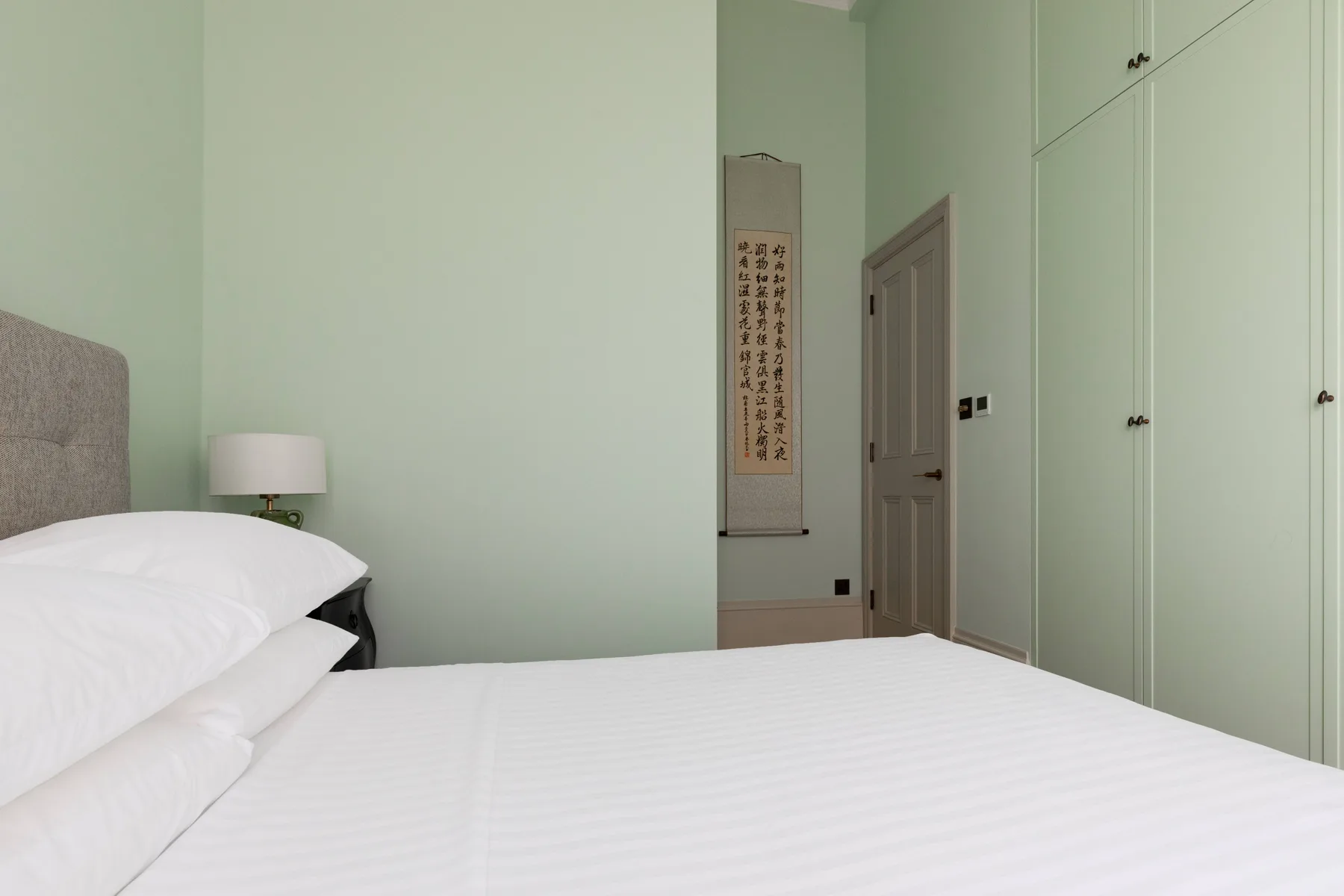 Un dormitorio con una cama bien hecha y armarios empotrados.