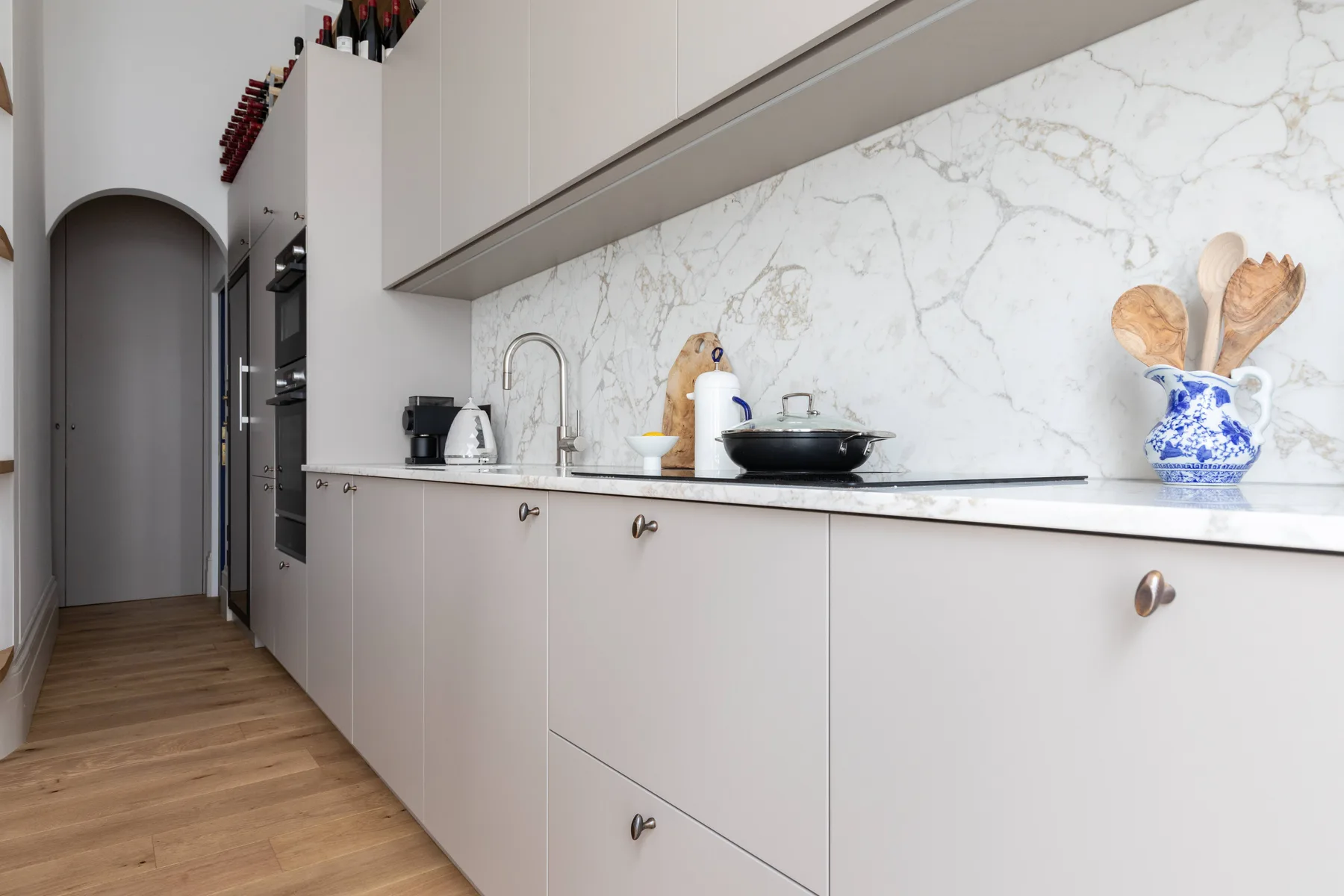 Una cocina moderna con gabinetes claros, un salpicadero veteado y electrodomésticos sobre la encimera.