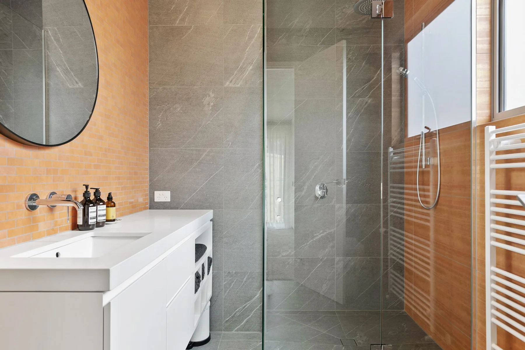 Un baño moderno con lavabo blanco y una ducha de vidrio.