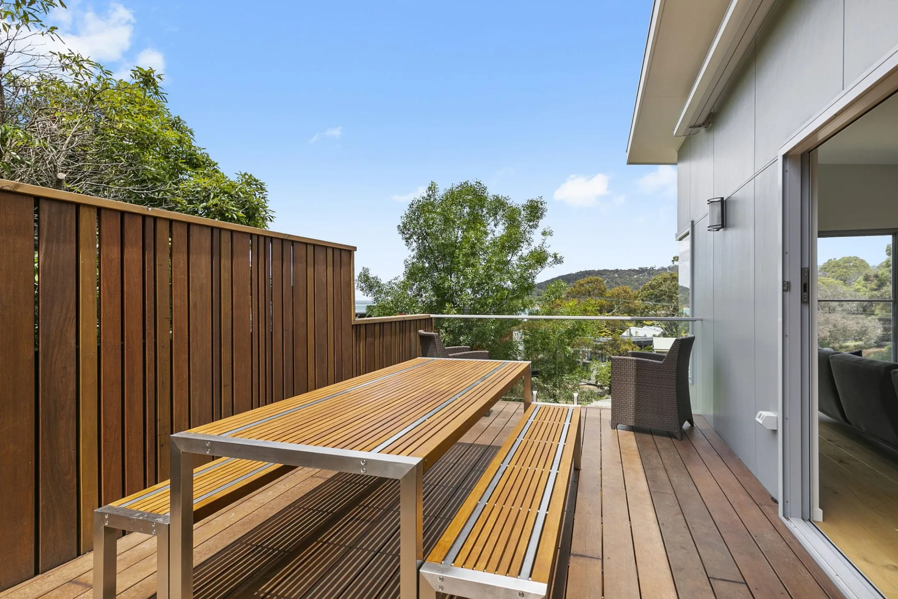 Una terraza exterior con asientos de madera y vistas a árboles y colinas.