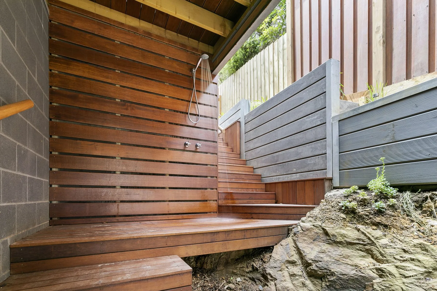 Zona de ducha exterior con tarima de madera y paneles de listones.