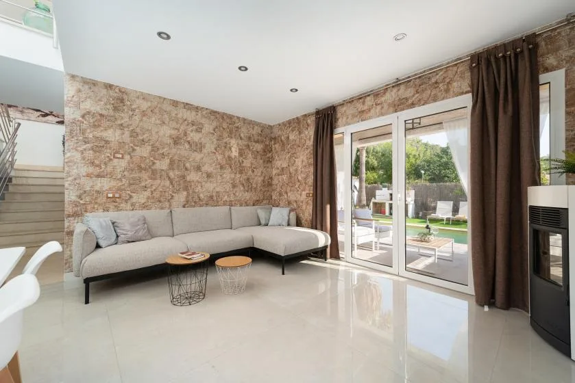 Una sala luminosa con asientos en forma de L y puertas de vidrio hacia un patio.