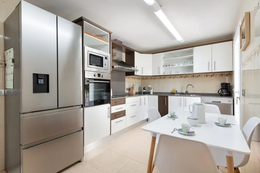 Una cocina moderna con gabinetes blancos y una mesa de comedor.
