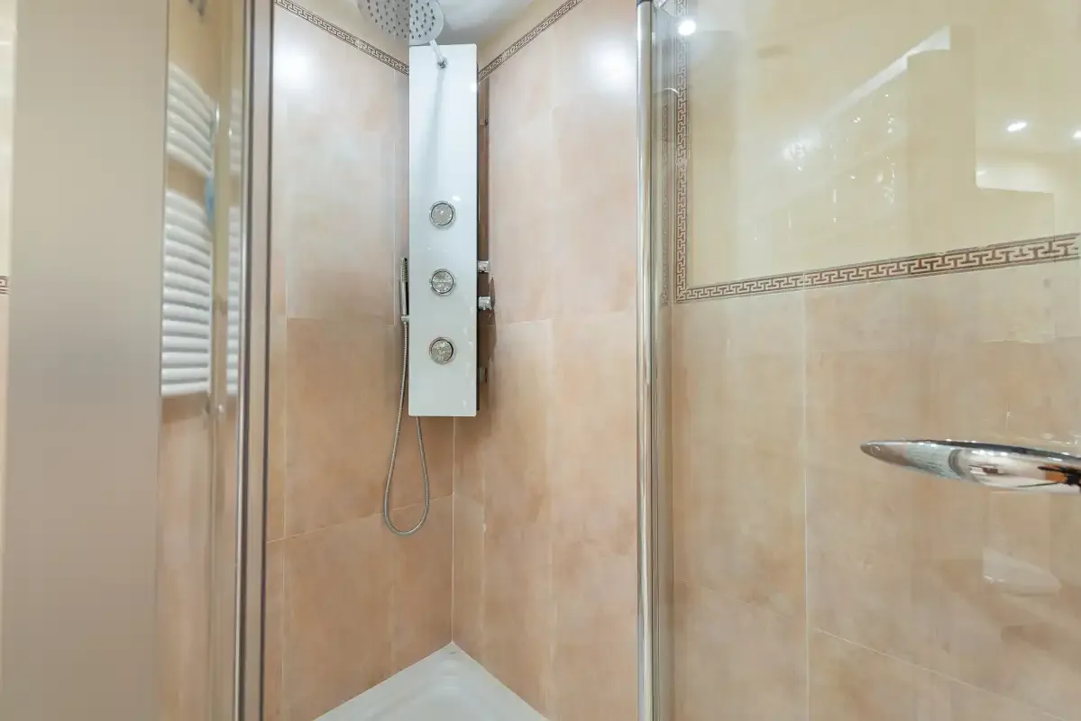 Una ducha de baño con azulejos y un panel de ducha en la pared.