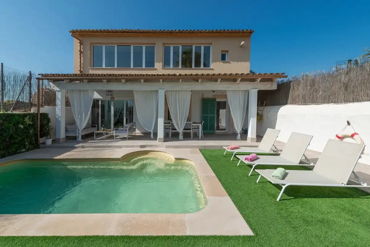 Una casa con piscina y asientos de descanso sobre el césped.