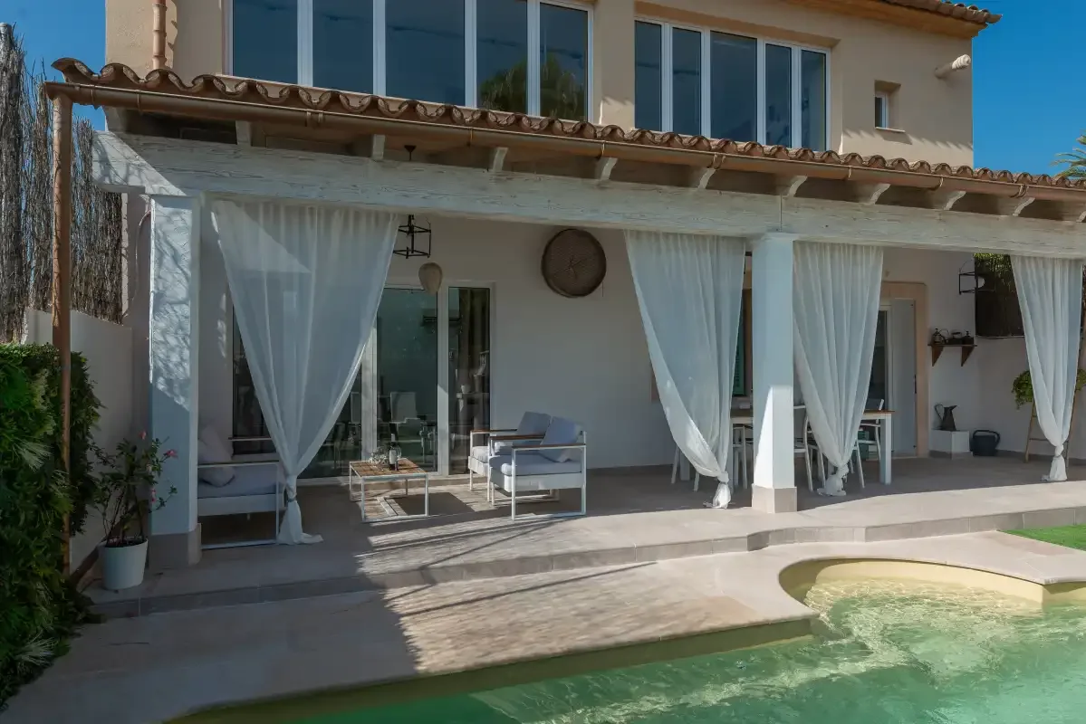 Un patio sombreado con asientos da a una piscina.