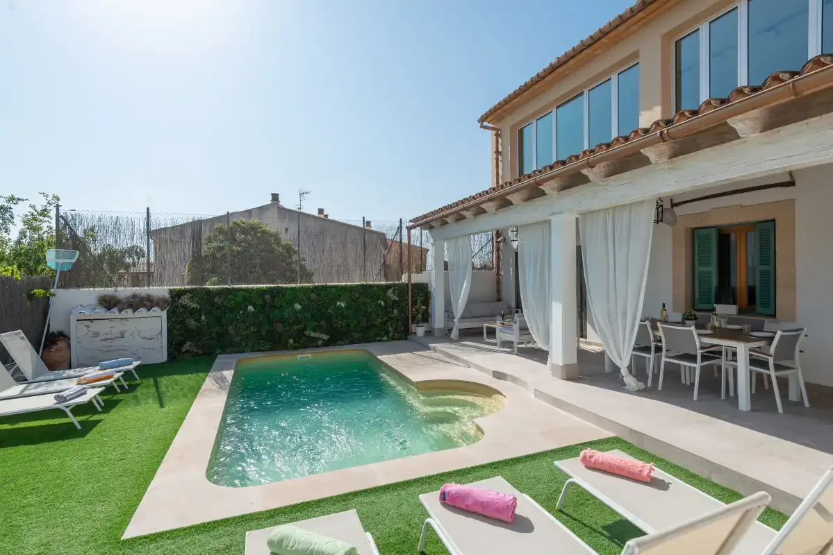 Piscina al aire libre y zona de estar junto a una casa.