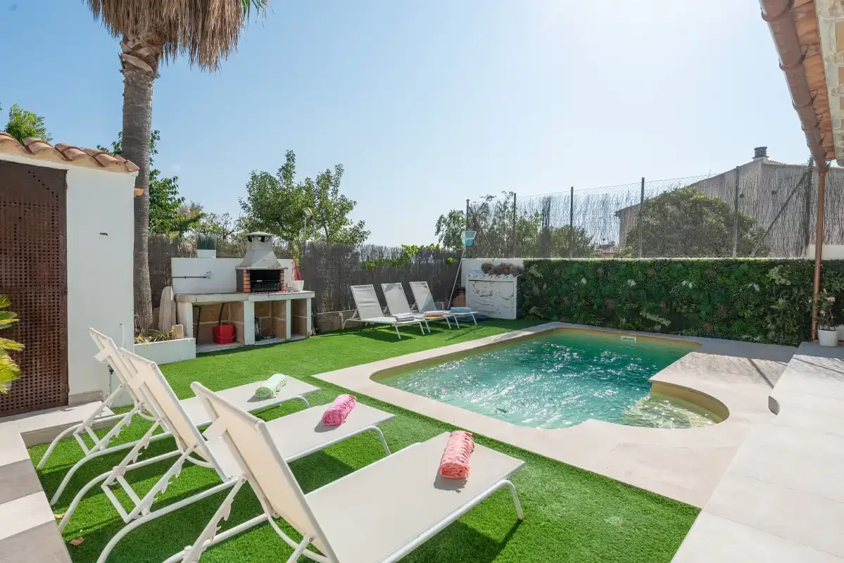Una zona de piscina al aire libre con tumbonas y una barbacoa.
