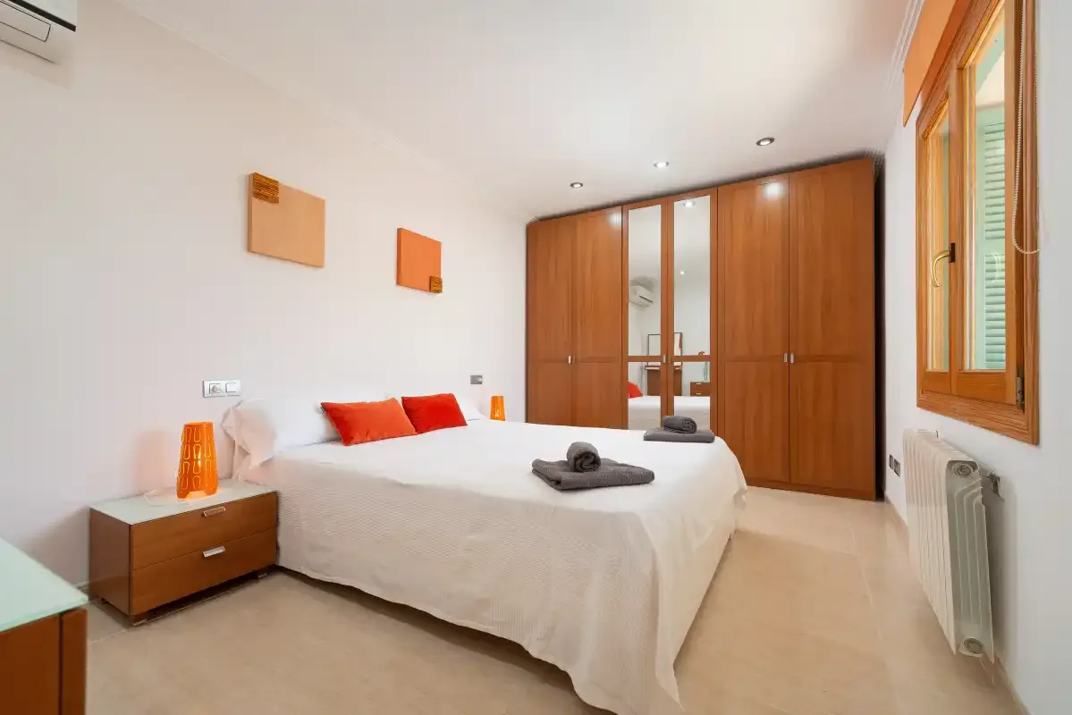 Un dormitorio luminoso con una cama bien hecha y armarios empotrados de madera.
