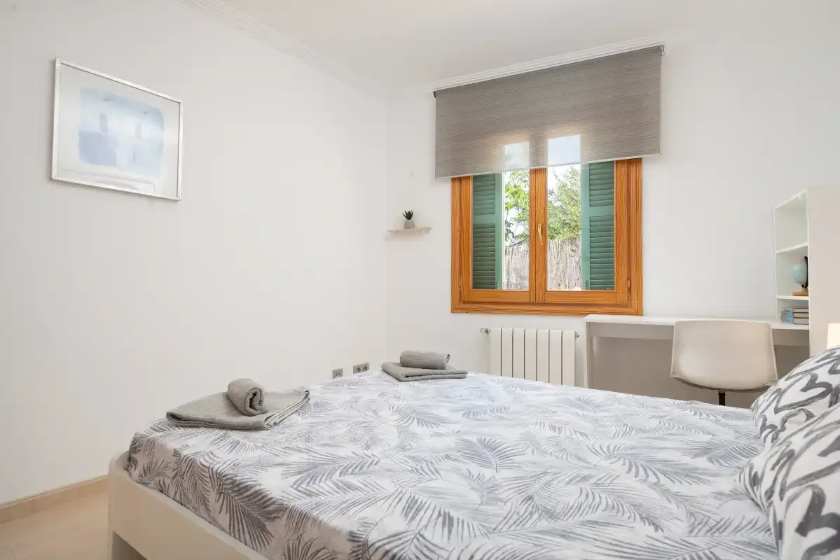 Un dormitorio con una cama bajo una ventana con contraventanas de madera.